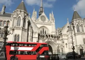 Red london bus driving past the London Royal court of justice